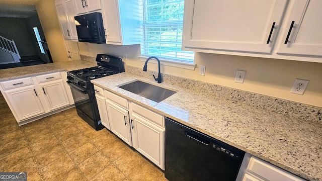 kitchen with white cabinetry, light stone countertops, black appliances, and a sink