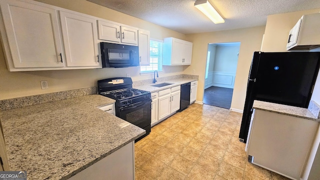 kitchen featuring white cabinetry, black appliances, a textured ceiling, and a sink