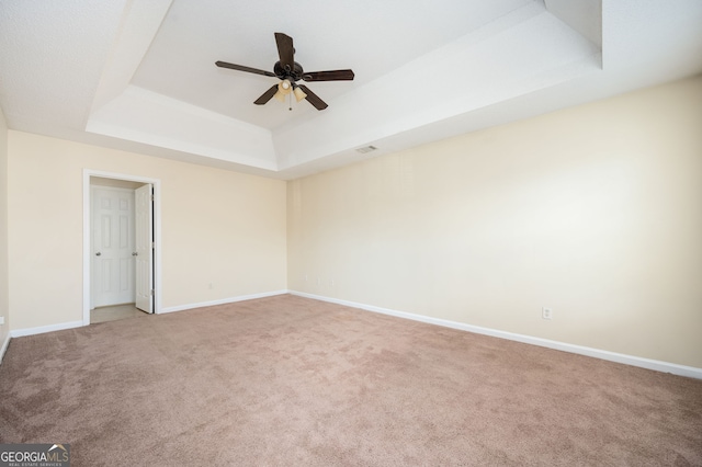 spare room featuring a tray ceiling, ceiling fan, carpet flooring, and baseboards