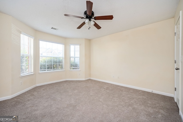 unfurnished room with carpet flooring, visible vents, and plenty of natural light