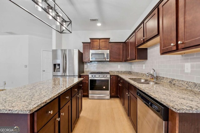 7431 Saint David St, Fairburn, GA 30213 - kitchen with appliances with stainless steel finishes, light wood-style floors, decorative backsplash, a kitchen island, and light stone counters