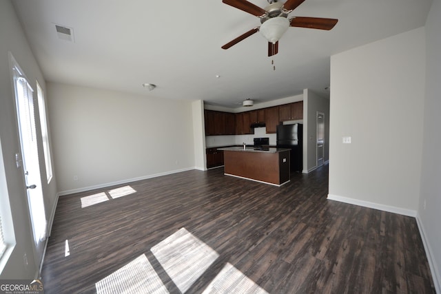 unfurnished living room featuring ceiling fan, baseboards, dark wood-style floors, and visible vents