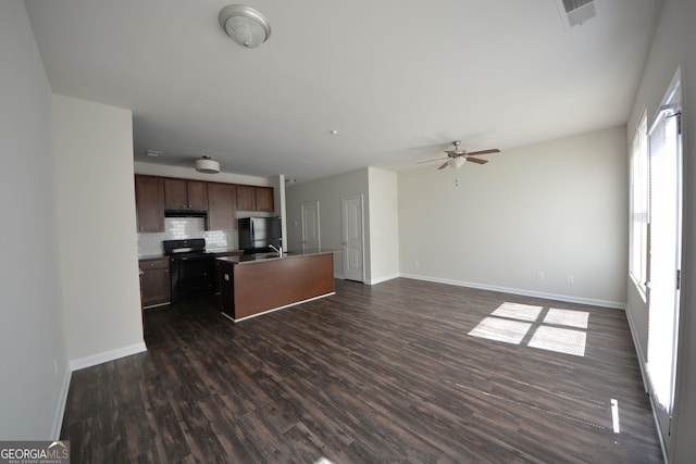 kitchen featuring visible vents, black appliances, open floor plan, a center island with sink, and dark wood-style floors