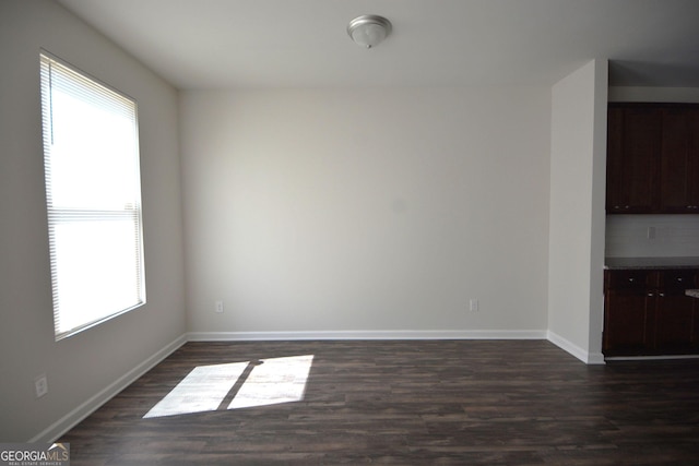 unfurnished dining area featuring baseboards and dark wood finished floors