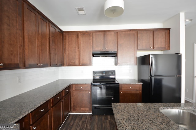 kitchen featuring visible vents, black appliances, dark stone counters, and under cabinet range hood