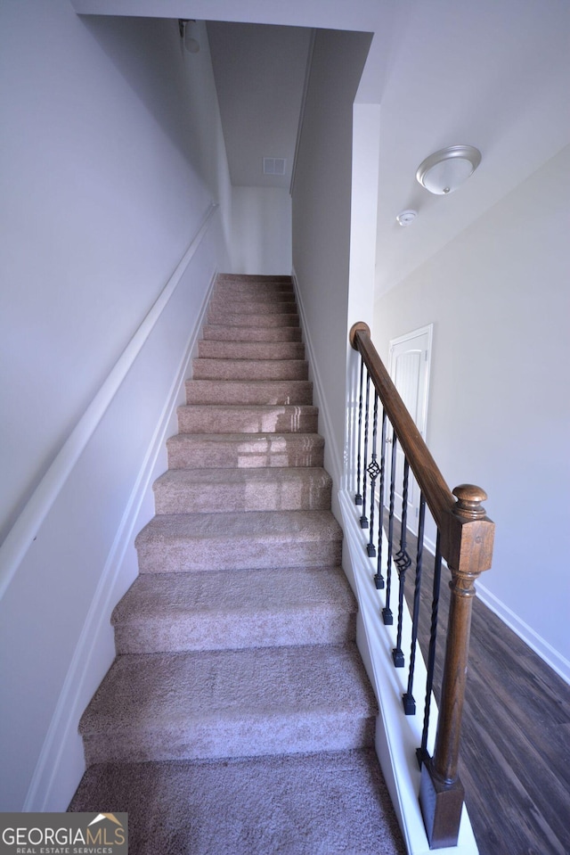stairs with visible vents and wood finished floors