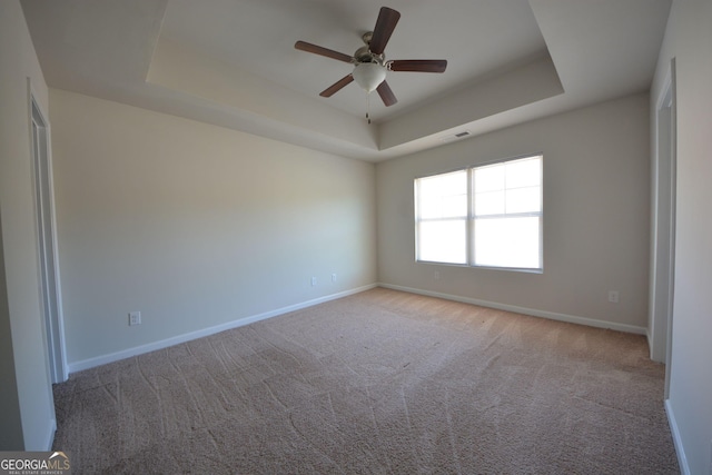 unfurnished room with ceiling fan, visible vents, baseboards, and a raised ceiling