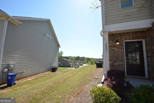 view of side of property featuring central AC, brick siding, and a lawn