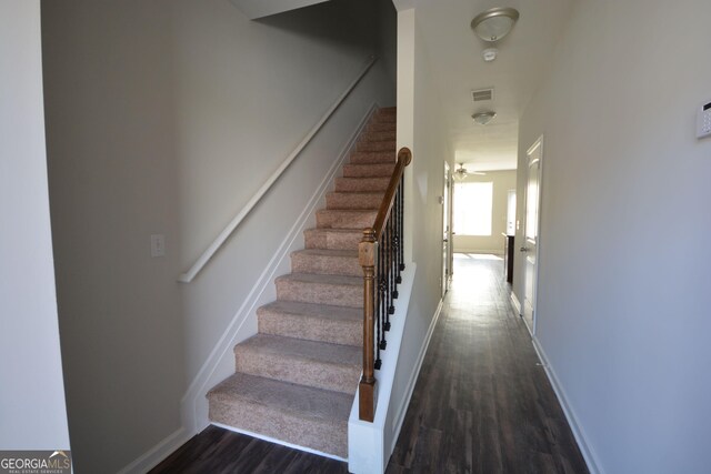 stairway featuring wood finished floors, baseboards, and visible vents