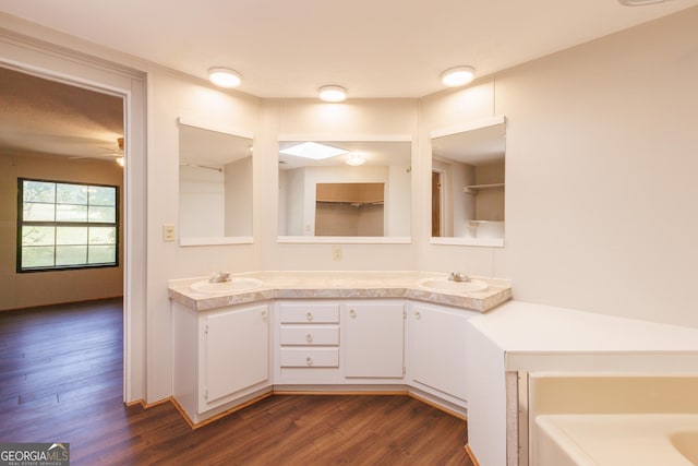 bathroom featuring ceiling fan, wood finished floors, double vanity, and a sink