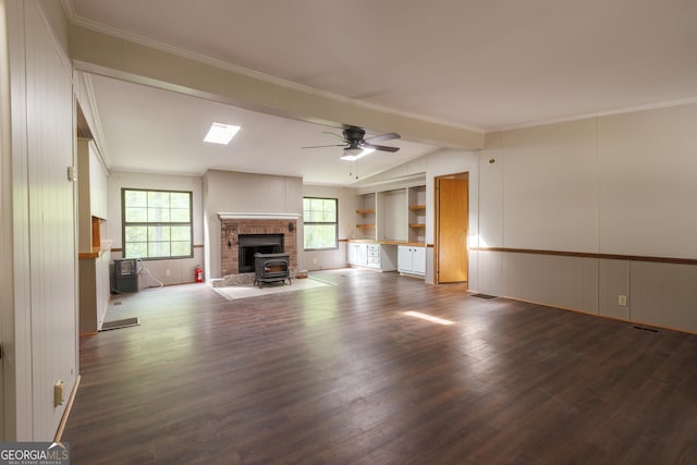 unfurnished living room with a wood stove, vaulted ceiling with beams, dark wood-type flooring, crown molding, and ceiling fan
