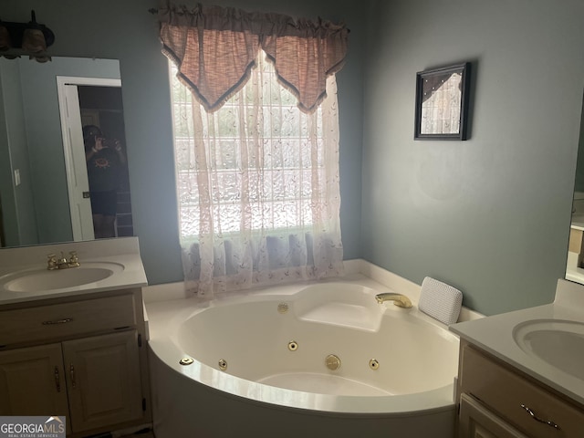 bathroom with a whirlpool tub, plenty of natural light, a sink, and two vanities