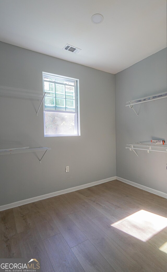 empty room featuring visible vents, baseboards, and wood finished floors