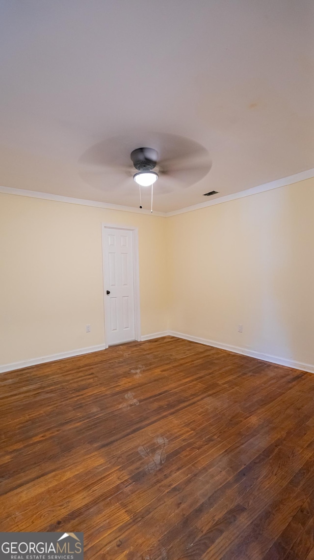 spare room with visible vents, baseboards, a ceiling fan, dark wood finished floors, and crown molding