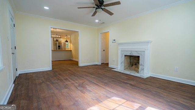 unfurnished living room with crown molding, a premium fireplace, wood finished floors, and ceiling fan with notable chandelier