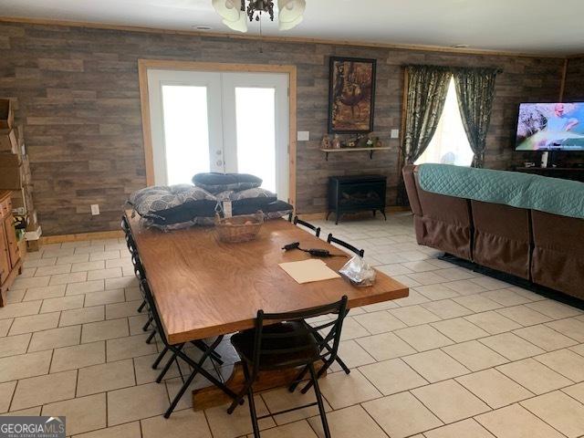 dining room featuring french doors, light tile patterned floors, and a wood stove