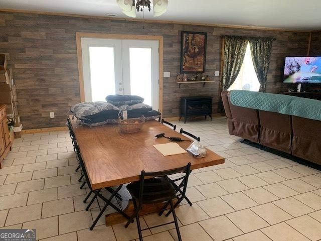 dining room with french doors, a wood stove, and light tile patterned floors