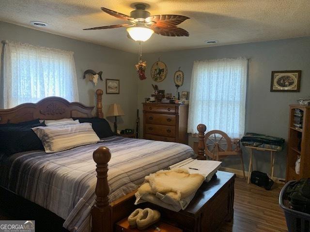 bedroom featuring a textured ceiling, wood finished floors, and a ceiling fan