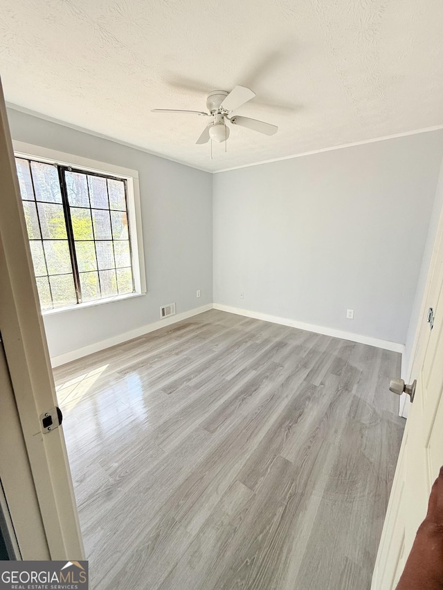 spare room with visible vents, baseboards, a ceiling fan, and wood finished floors