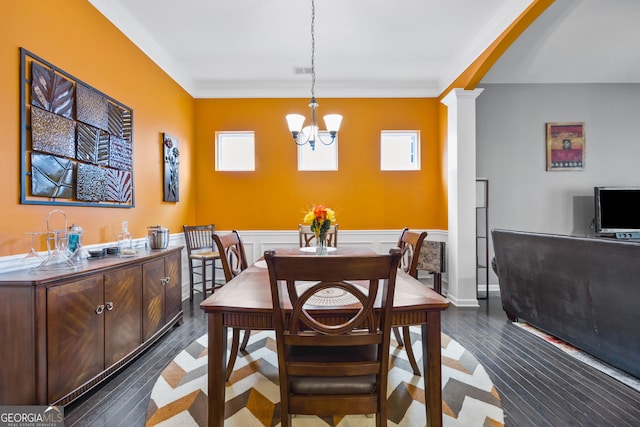 dining area featuring visible vents, crown molding, wood finished floors, a notable chandelier, and ornate columns