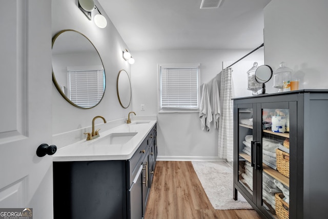 full bath with double vanity, wood finished floors, visible vents, and a sink