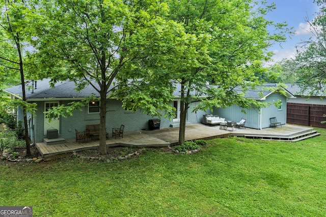 rear view of property with a wooden deck, a lawn, fence, and roof with shingles