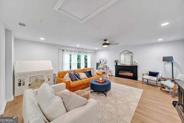 living area with a glass covered fireplace, light wood-style flooring, visible vents, and recessed lighting