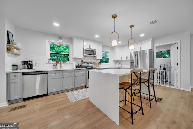 kitchen with a breakfast bar, visible vents, appliances with stainless steel finishes, and gray cabinets