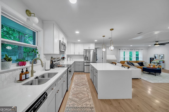 kitchen with stainless steel appliances, visible vents, a sink, a kitchen island, and gray cabinetry