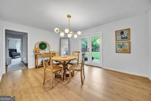 dining space featuring light wood-style flooring, baseboards, and an inviting chandelier