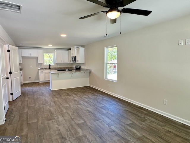 kitchen with a peninsula, white cabinetry, visible vents, dark wood finished floors, and appliances with stainless steel finishes