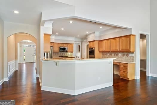 1330 Badingham Dr, Cumming, GA 30041 - kitchen featuring stainless steel appliances, arched walkways, backsplash, dark wood-style floors, and recessed lighting