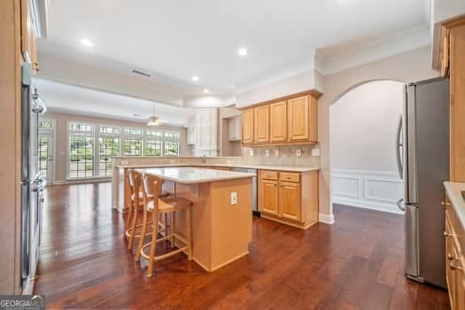 1330 Badingham Dr, Cumming, GA 30041 - kitchen with stainless steel appliances, light countertops, light brown cabinets, dark wood finished floors, and a peninsula