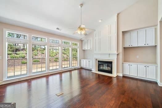 1330 Badingham Dr, Cumming, GA 30041 - unfurnished living room featuring ceiling fan, dark wood-type flooring, a glass covered fireplace, and vaulted ceiling