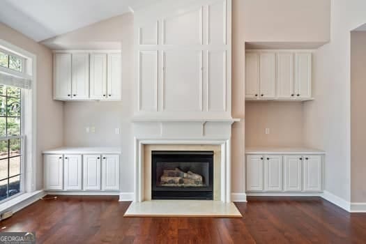 1330 Badingham Dr, Cumming, GA 30041 - unfurnished living room with dark wood-style flooring, a glass covered fireplace, and vaulted ceiling