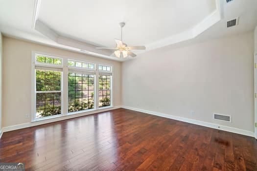 1330 Badingham Dr, Cumming, GA 30041 - unfurnished room featuring a tray ceiling, ceiling fan, and wood finished floors