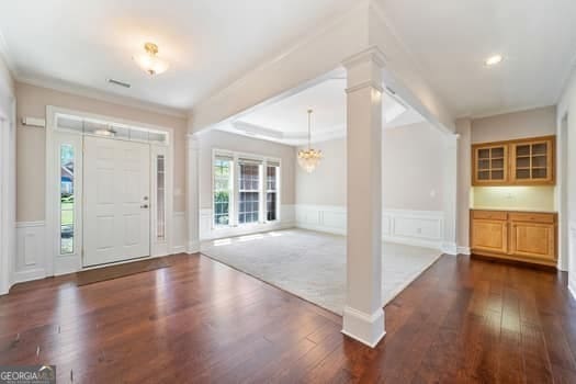 1330 Badingham Dr, Cumming, GA 30041 - entryway with a chandelier, dark wood-style flooring, a wainscoted wall, and a decorative wall