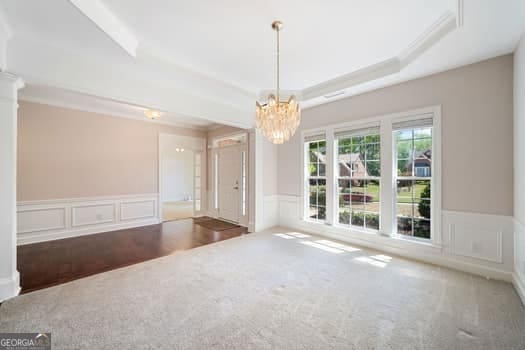 1330 Badingham Dr, Cumming, GA 30041 - carpeted spare room featuring a wainscoted wall, a chandelier, a decorative wall, a raised ceiling, and crown molding