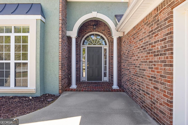 entrance to property featuring stucco siding and brick siding