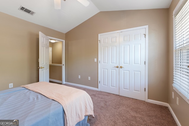 carpeted bedroom with baseboards, a closet, vaulted ceiling, a ceiling fan, and visible vents
