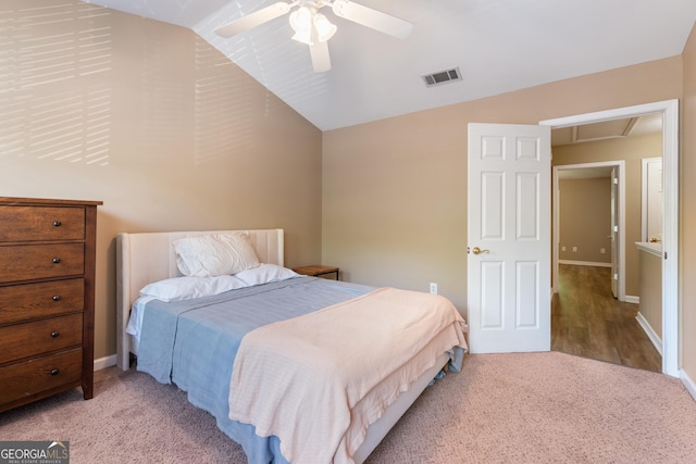 bedroom with a ceiling fan, visible vents, attic access, carpet flooring, and lofted ceiling