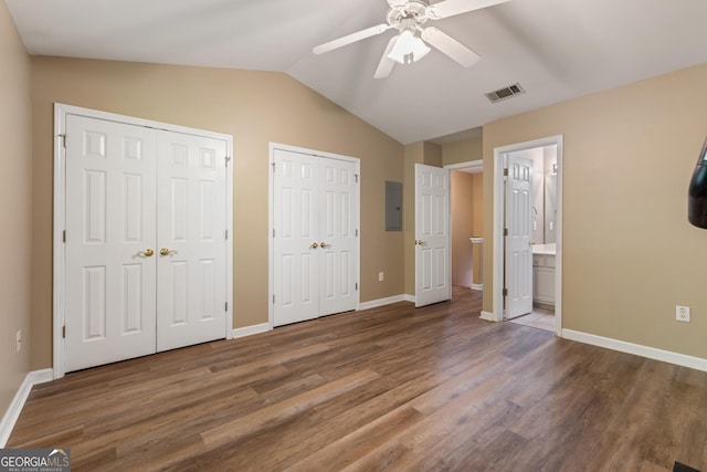 unfurnished bedroom with electric panel, visible vents, multiple closets, lofted ceiling, and wood finished floors
