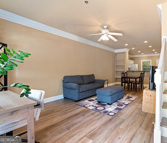 living area featuring light wood-type flooring, baseboards, recessed lighting, crown molding, and ceiling fan