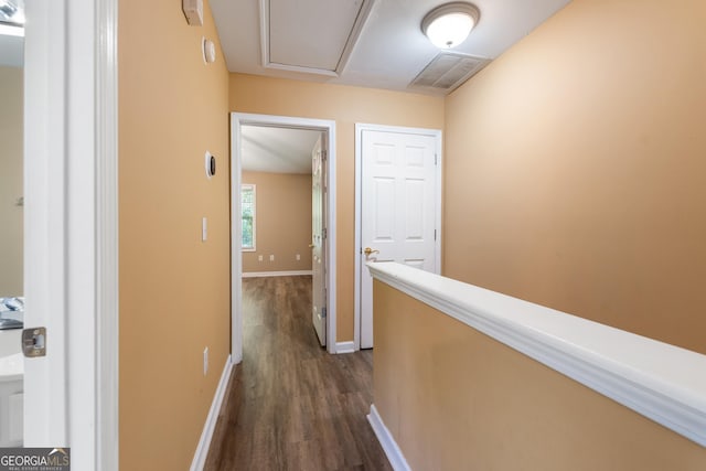 hall featuring dark wood-type flooring, attic access, baseboards, and visible vents