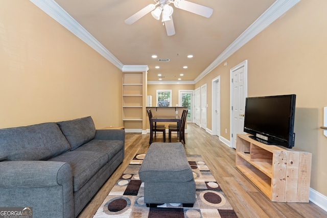 living area featuring baseboards, light wood-type flooring, ornamental molding, recessed lighting, and ceiling fan