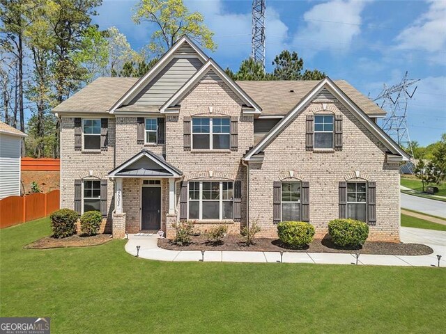 craftsman inspired home featuring fence, a front lawn, and brick siding