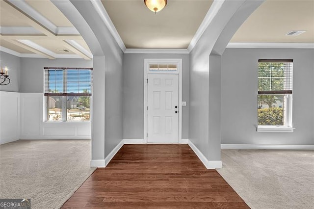 entrance foyer featuring an inviting chandelier, ornamental molding, arched walkways, and carpet