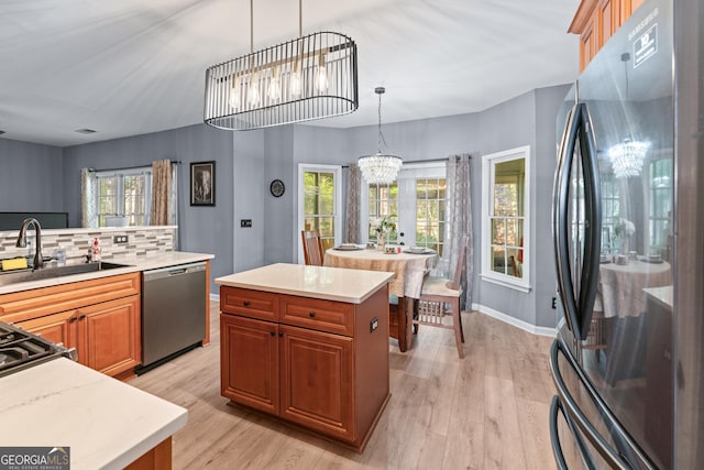 kitchen featuring a notable chandelier, a sink, light countertops, light wood finished floors, and stainless steel appliances