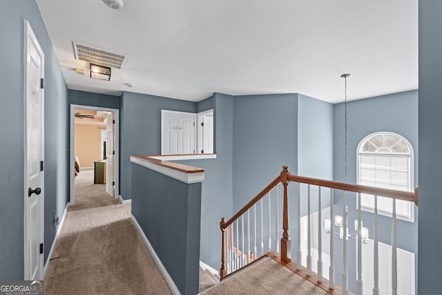 corridor featuring carpet flooring, an upstairs landing, visible vents, and baseboards