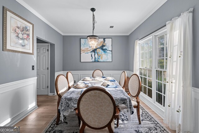 1035 Bridle Path Dr, Lawrenceville, GA 30045 - dining space with a chandelier, ornamental molding, light wood-style floors, a wainscoted wall, and a decorative wall
